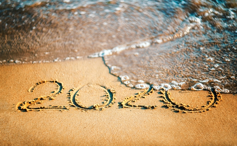Waves begin to wash away 2020 written in the sand